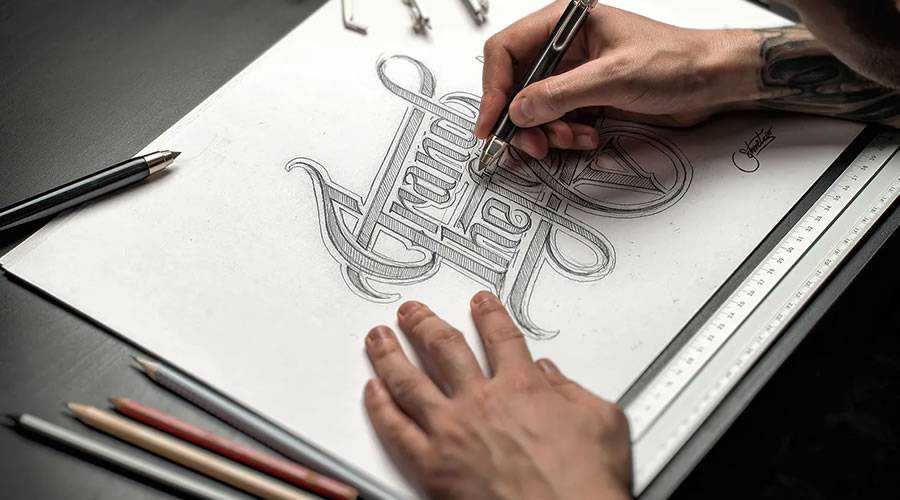 Hand-drawn pencil sketch of a custom logo concept on paper with drafting tools